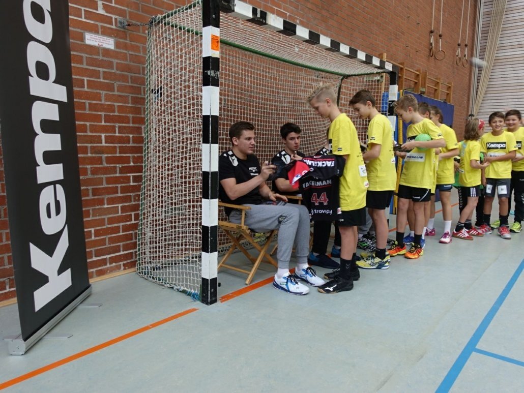Kinder unterschreiben ihre Trikots von Handballprofis