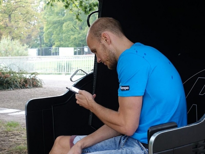 Tim Hornke schaut entspannt auf sein Handy im Kempa Strandkorb