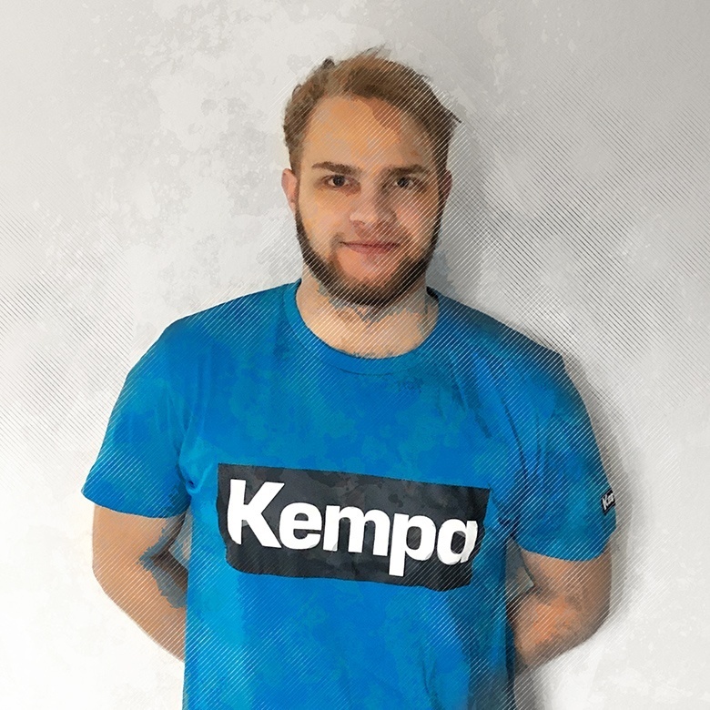 Alexander Reimann im blauen Kempa T-Shirt und die Arme nach hinten verschränkt